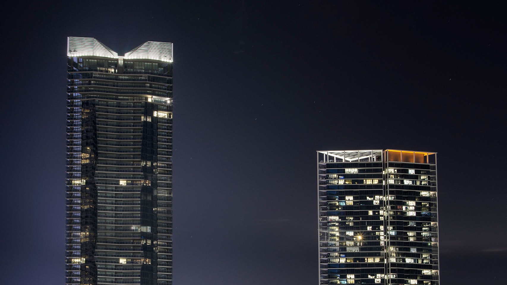 Maxis high-power linear flood light  in application, installed on Yarra Point (Tower 6). Maxis high-powered projector luminaires, complete with flare optics, are used to illuminate the architectural crown of the building.