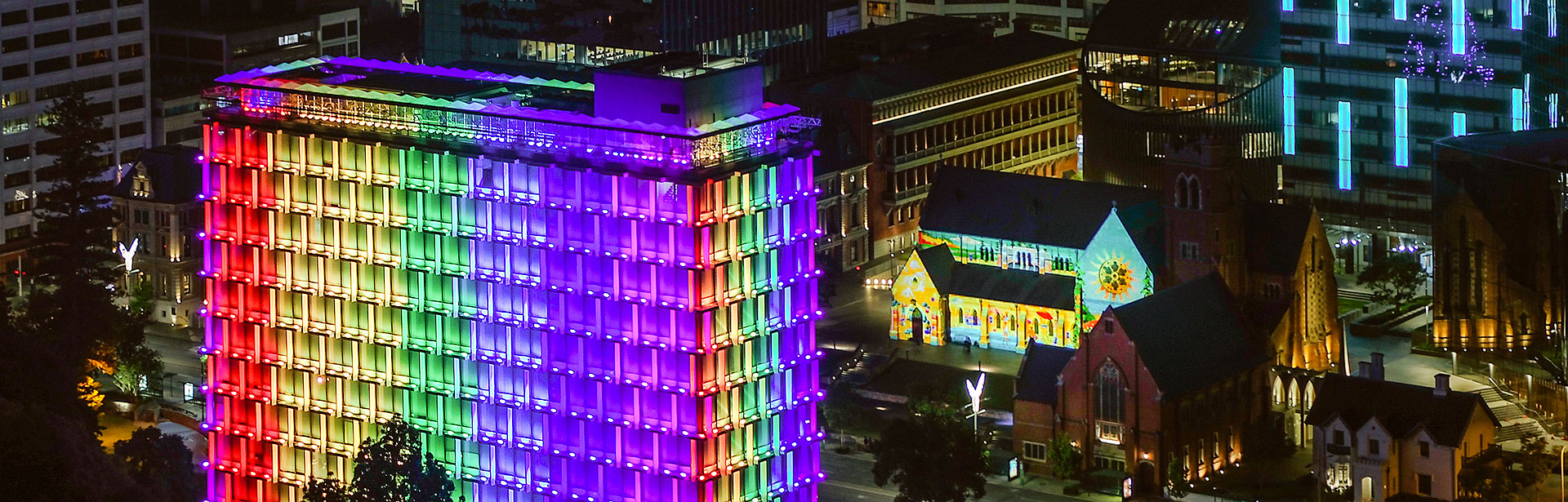 Latitude LED luminaire in application, installed on the facade on Council House in Perth. Colour changing feature is illustrated, the building is illuminated in rainbow colours. 
